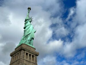 Iconic view of the Statue of Liberty under a partly cloudy sky, representing freedom.