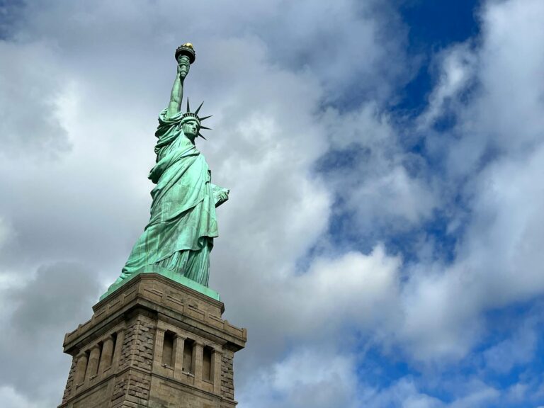 Iconic view of the Statue of Liberty under a partly cloudy sky, representing freedom.